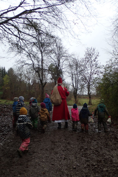 Der Nikolaus geht mit den Kindern durch den Wald.