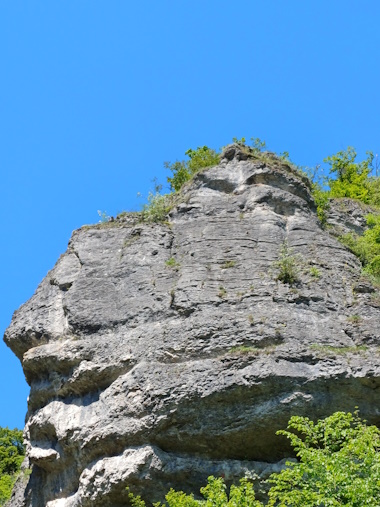 Blick nach oben in den blauen Himmel, entlang eines Felsens