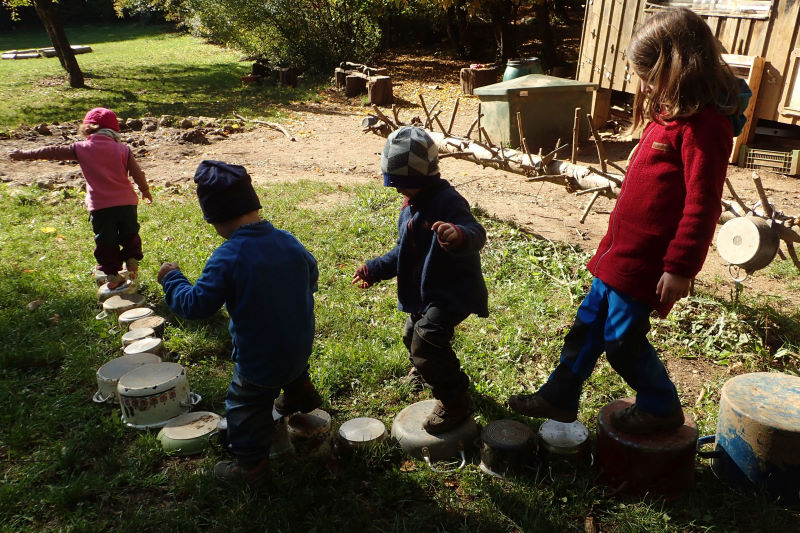 Kinder balancieren über eine Bahn aus alten Kochtöpfen